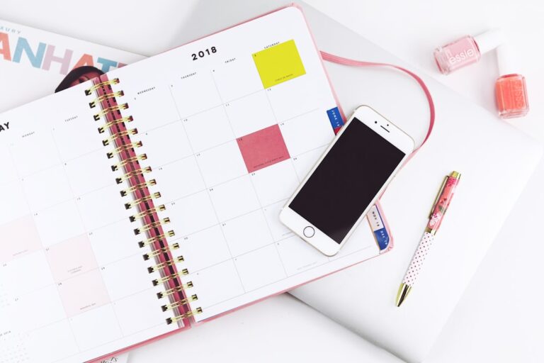 明るいデスクで手帳とスマートフォンを使って予定を整理するイメージ。Photo by Hey Beauti Magazine on Unsplash